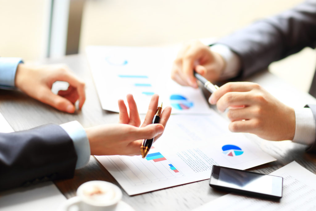 Image of two young businessmen discussing document  at meeting